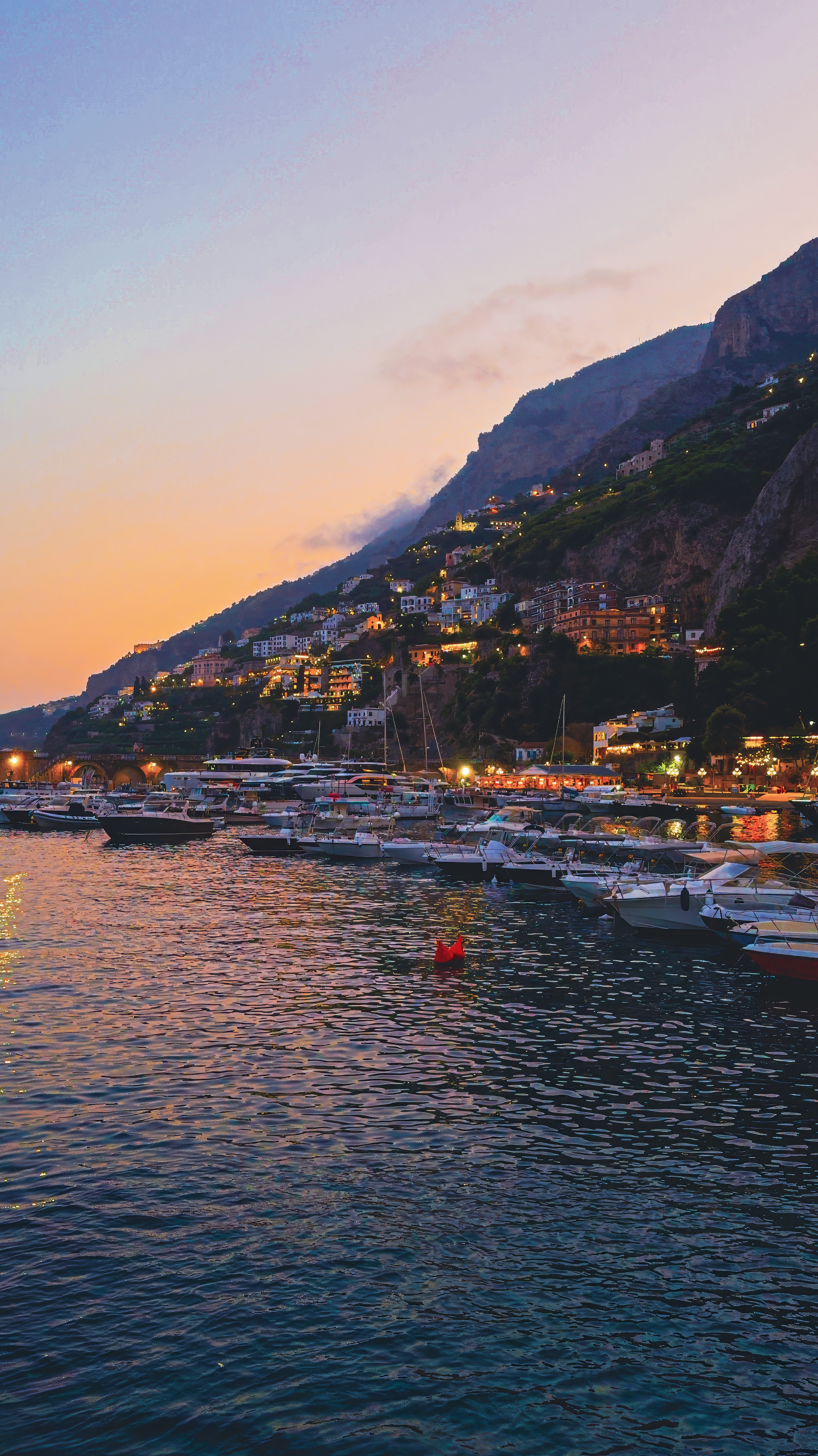 Amalfi harbour at dusk, with the town lights along the mountainside.