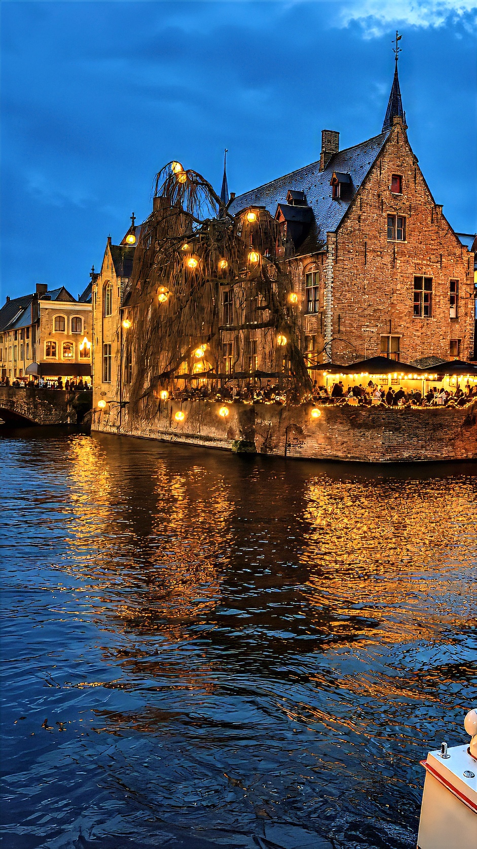 A canal-side house lit up at night, its reflection in the dark water.