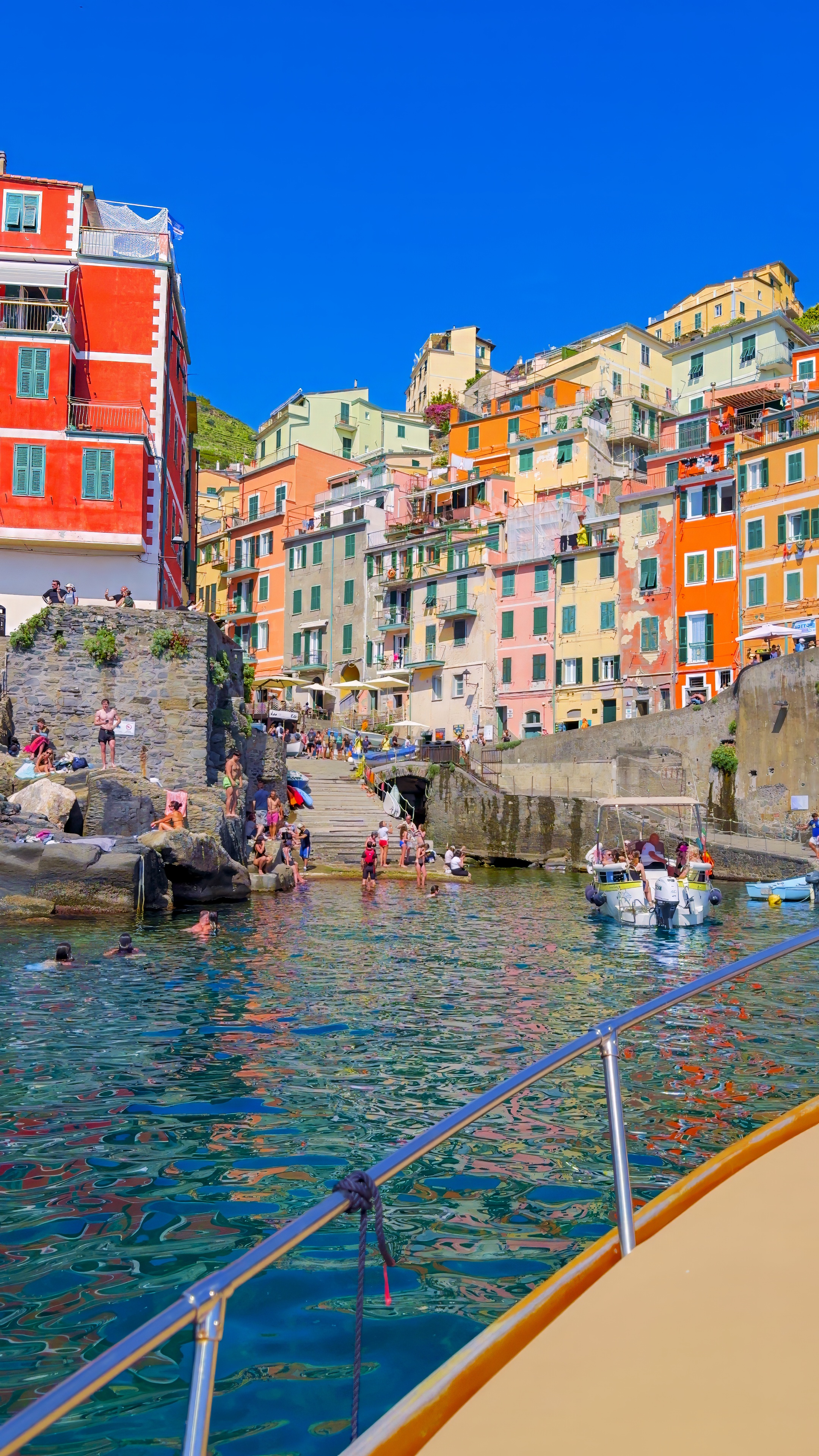 Riomaggiore seen from the water, a tall red house at the edge of the coloured village.