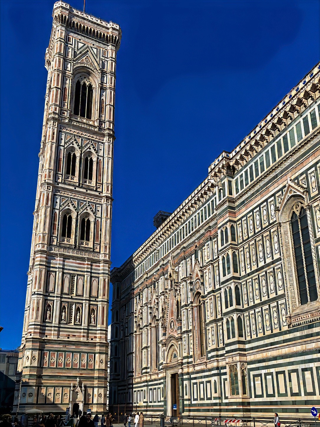 Giotto's Bell Tower in green, white and pink marble beside the flank of the cathedral.