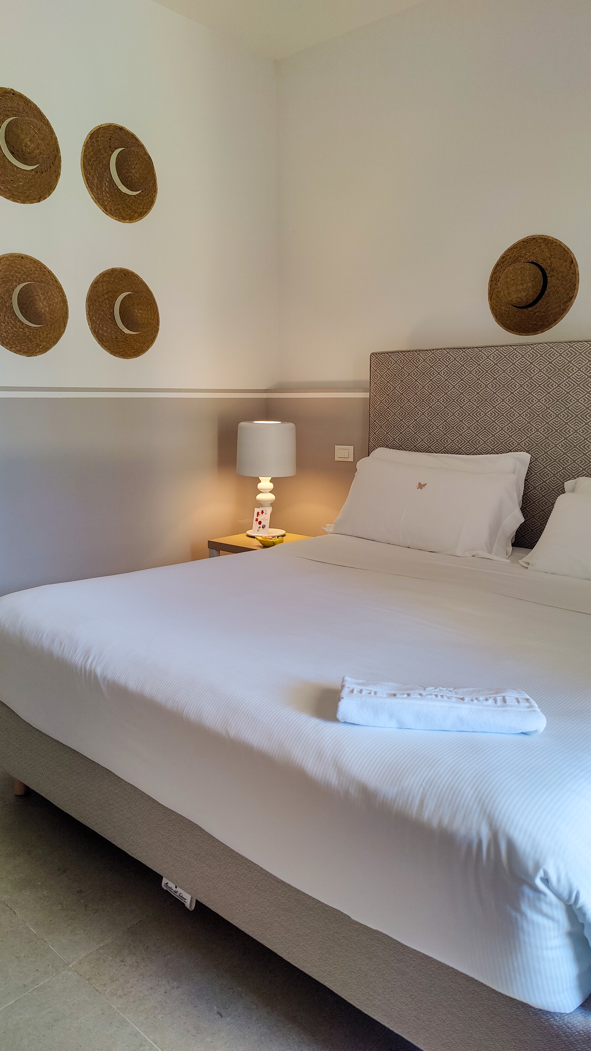Our room: a white bed with a woven headboard, a bedside lamp and woven baskets on the wall