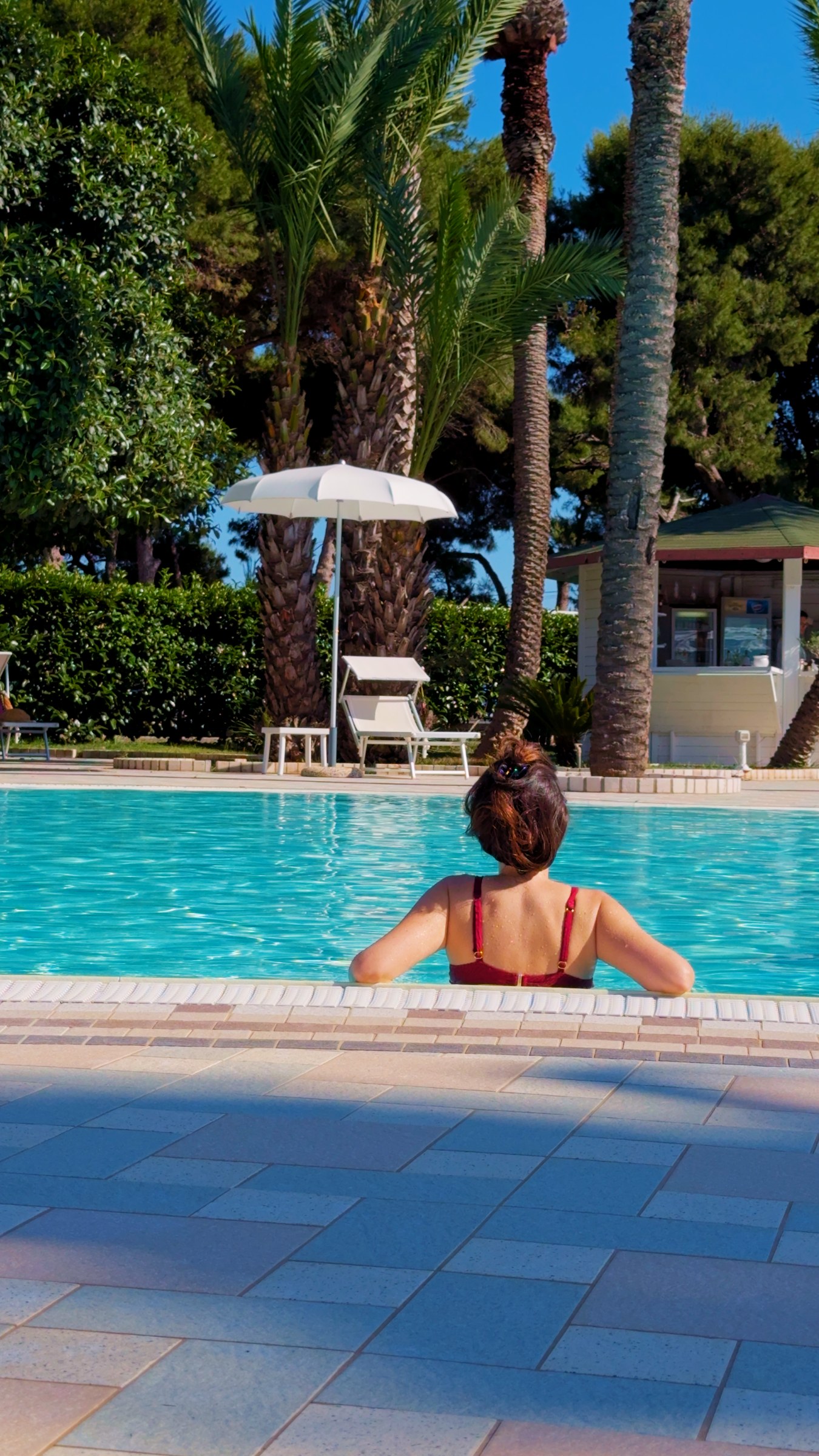 Barbara in the pool at Giardino dei Pini, with palms and pines behind.