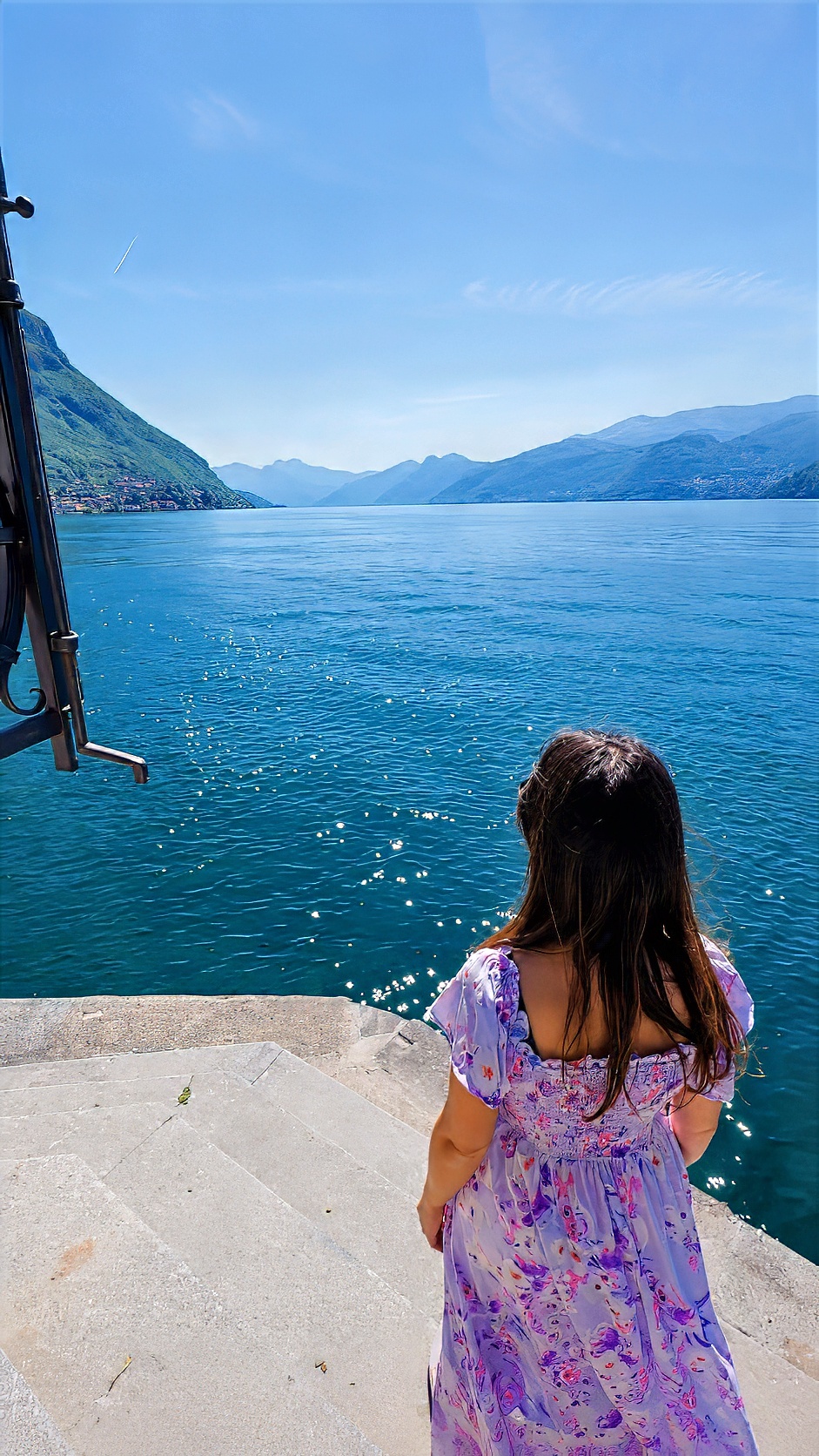 Barbara seen from behind at a viewpoint above the lake, looking across the water to the mountains.