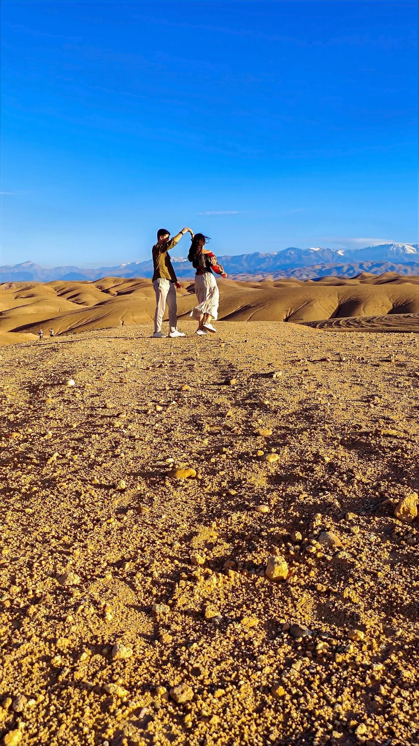 A couple dancing in the Agafay desert with the Atlas Mountains in the distance.