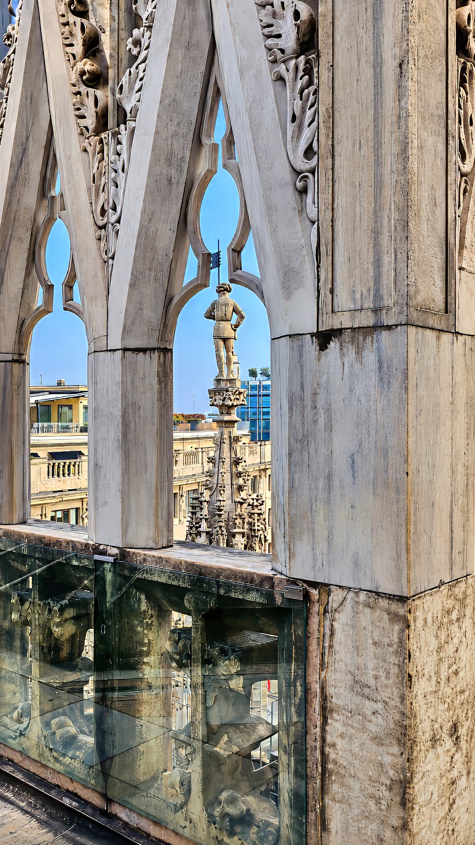 Carved marble tracery and pinnacles framing a view across the cathedral roof.