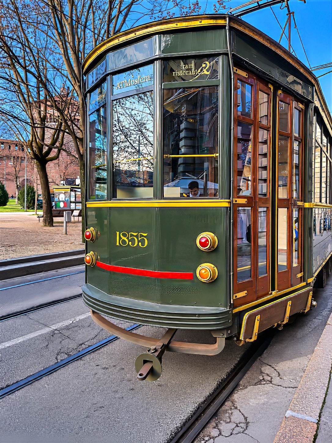 A green historic tram on the rails of a city street.