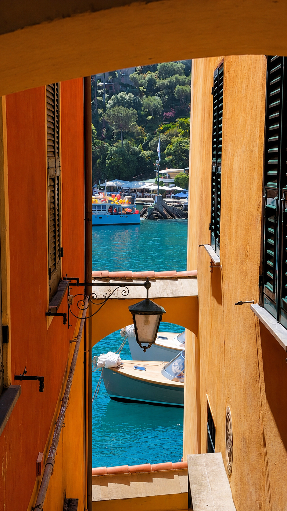 The harbour seen through a narrow passage between ochre walls, with boats on the water.