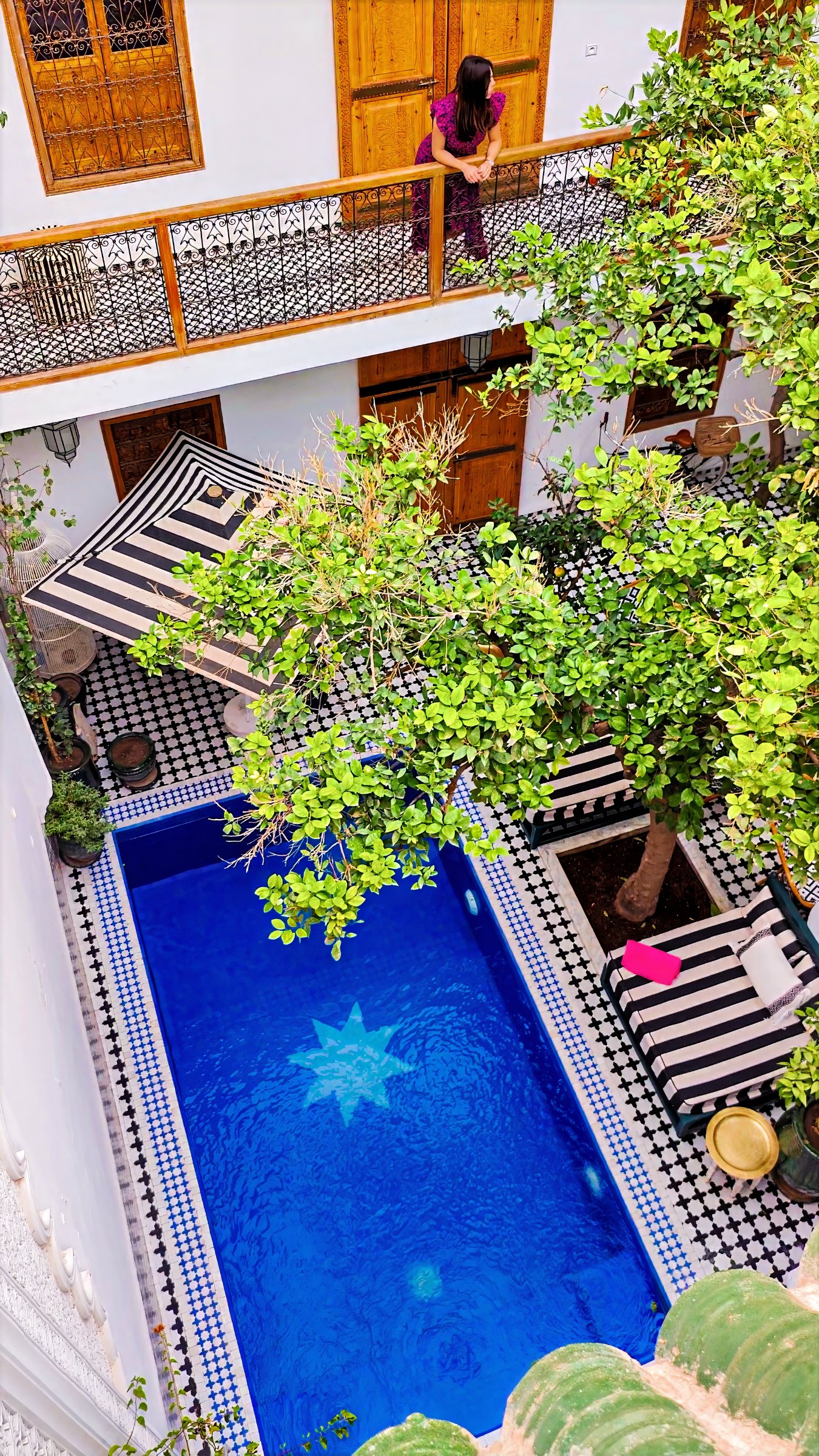 The courtyard from above: a pool with a star motif in the tiles, trees and plants around it