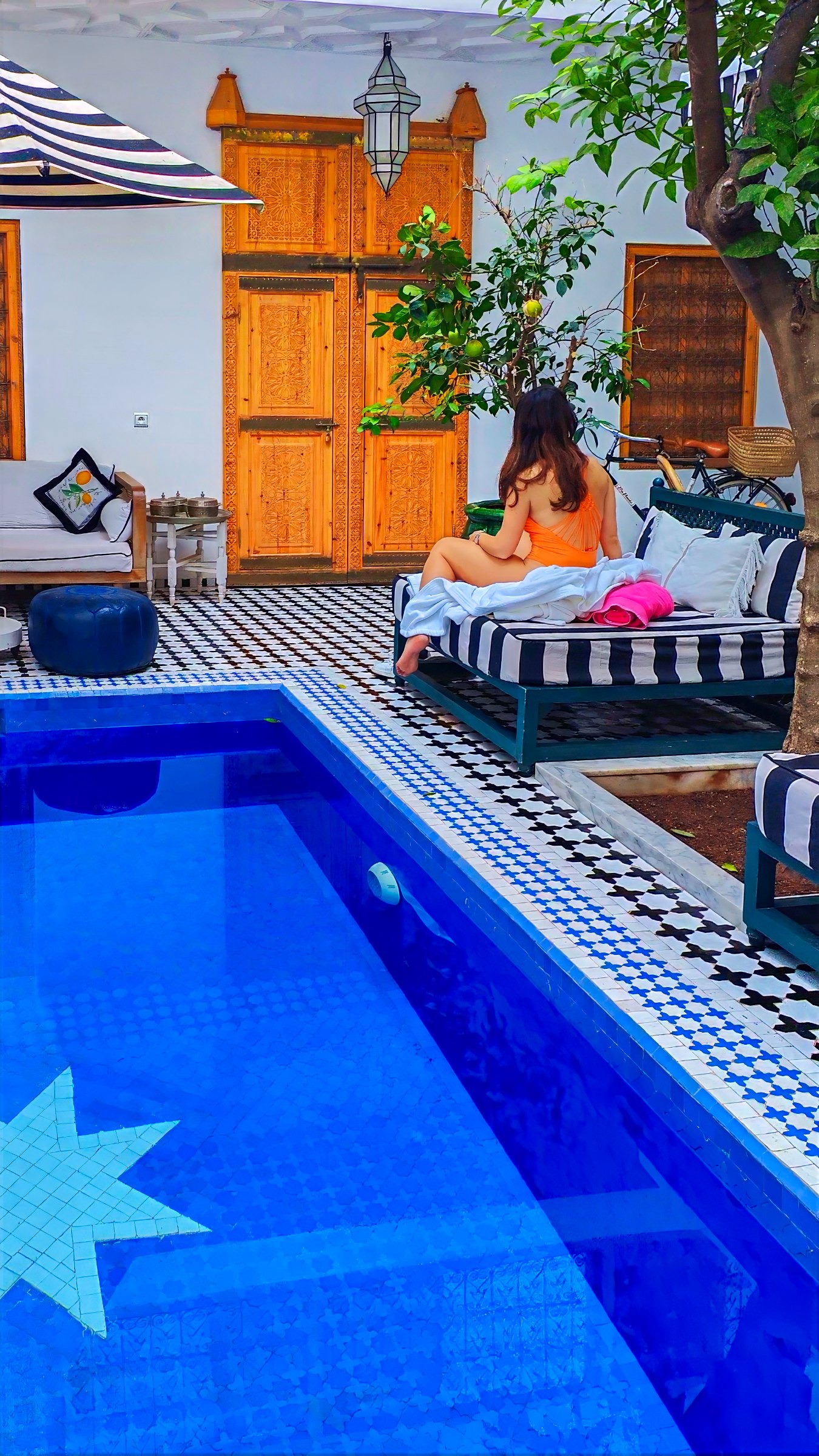 One of us beside the courtyard pool, next to tall carved wooden doors