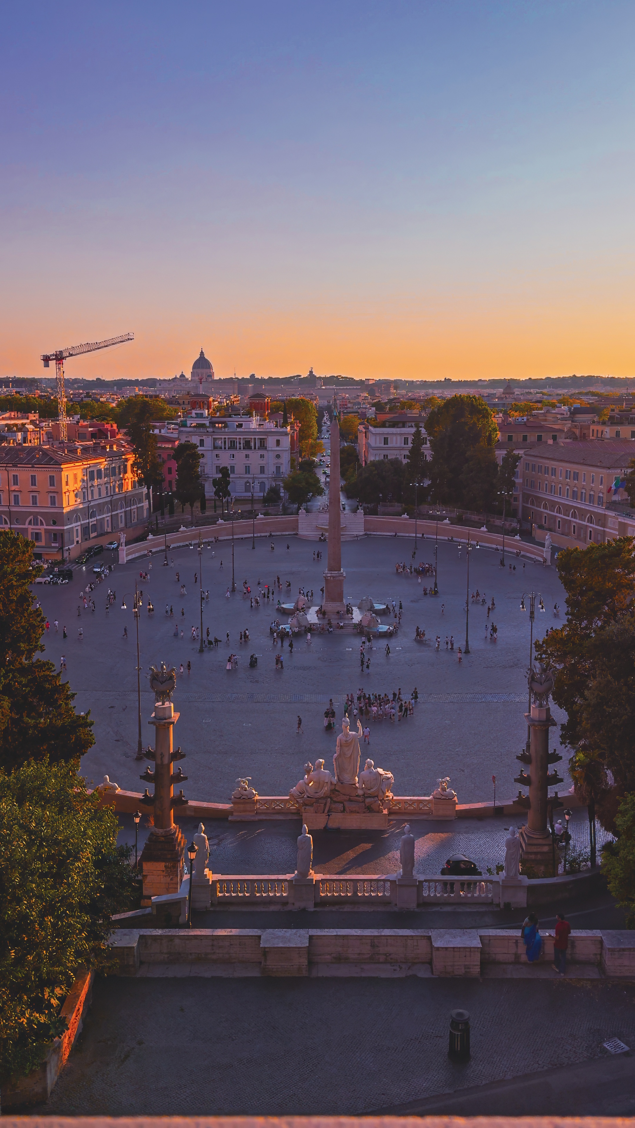 The oval of Piazza del Popolo with its obelisk and twin churches, seen from the Pincio terrace at dusk.