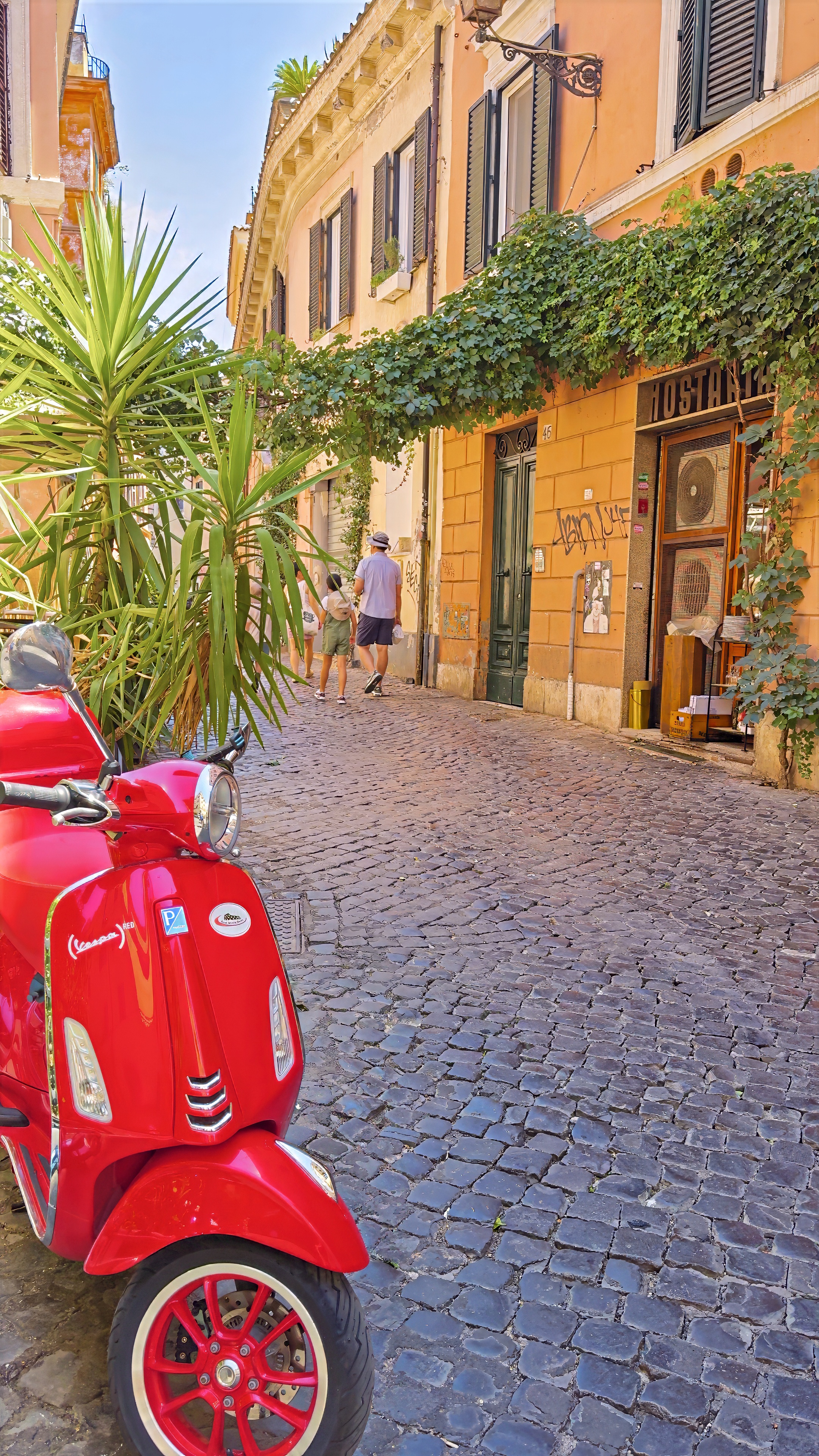 A cobbled lane in Trastevere with a red Vespa by an osteria