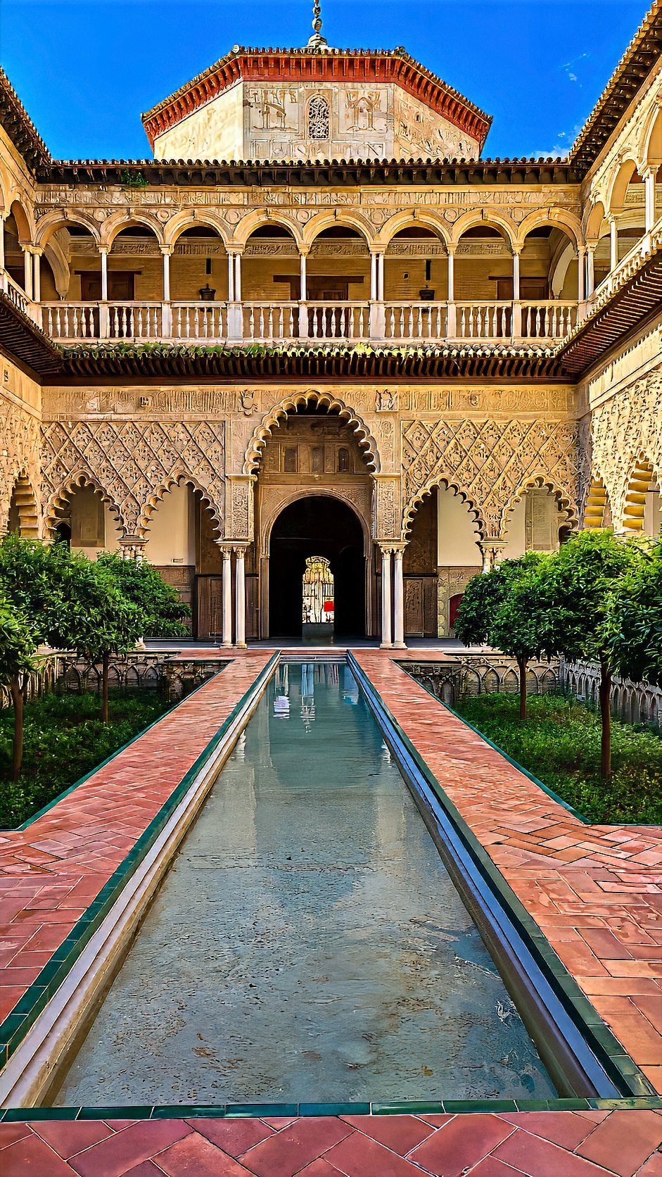 The long reflecting pool of the Patio de las Doncellas, framed by carved arcades and orange trees