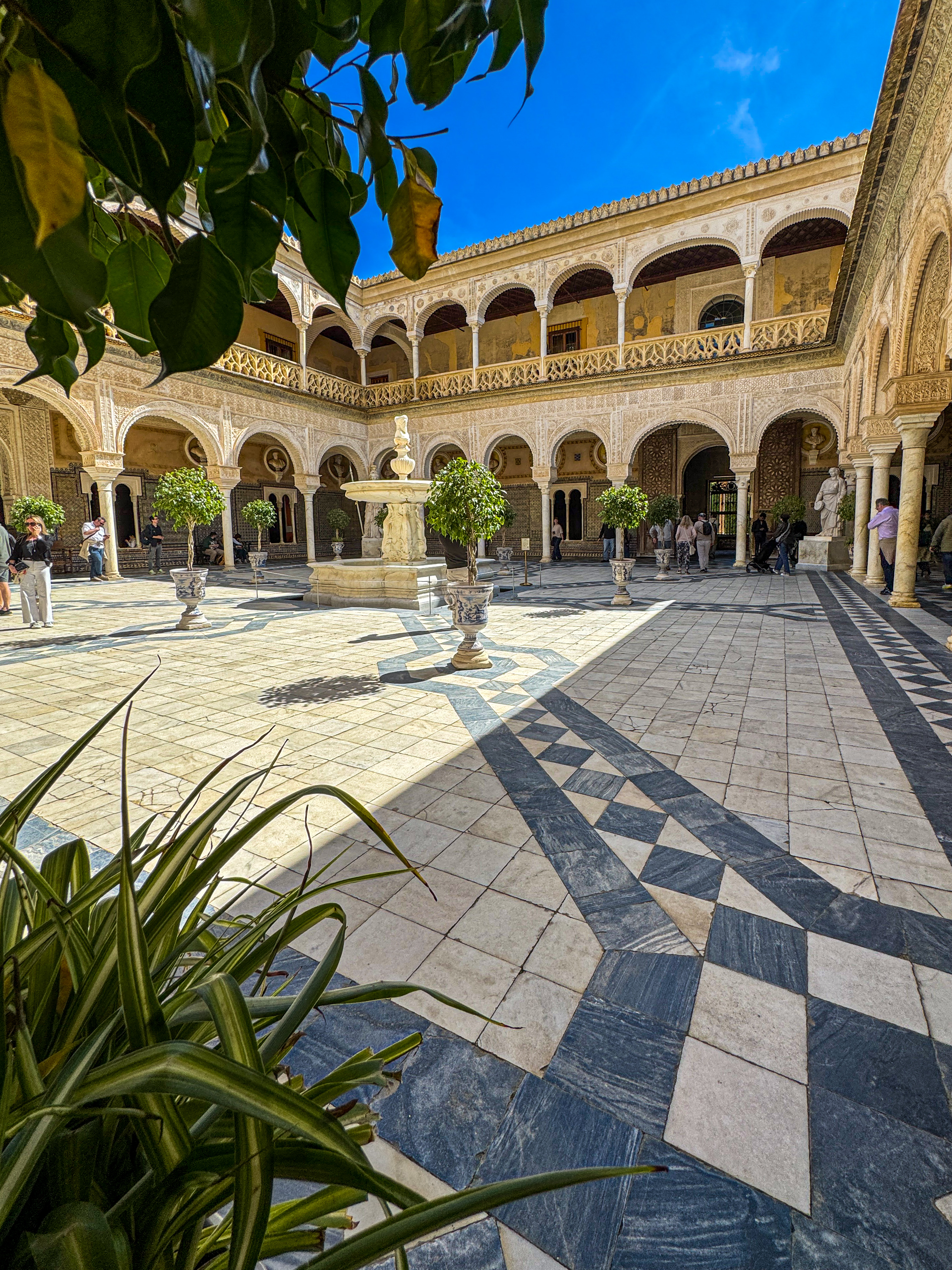 The arcaded main courtyard of Casa de Pilatos, with a central fountain and a chequered stone floor