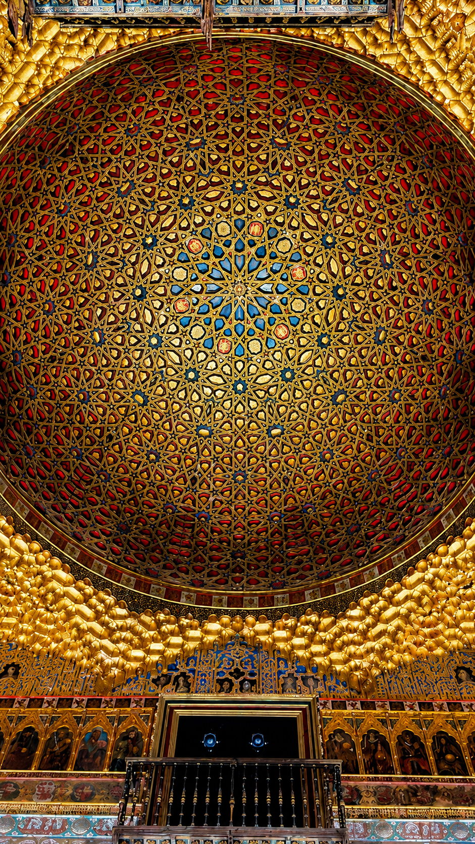 A gilded dome inside the Real Alcázar, carved in intricate geometric patterns above a balcony