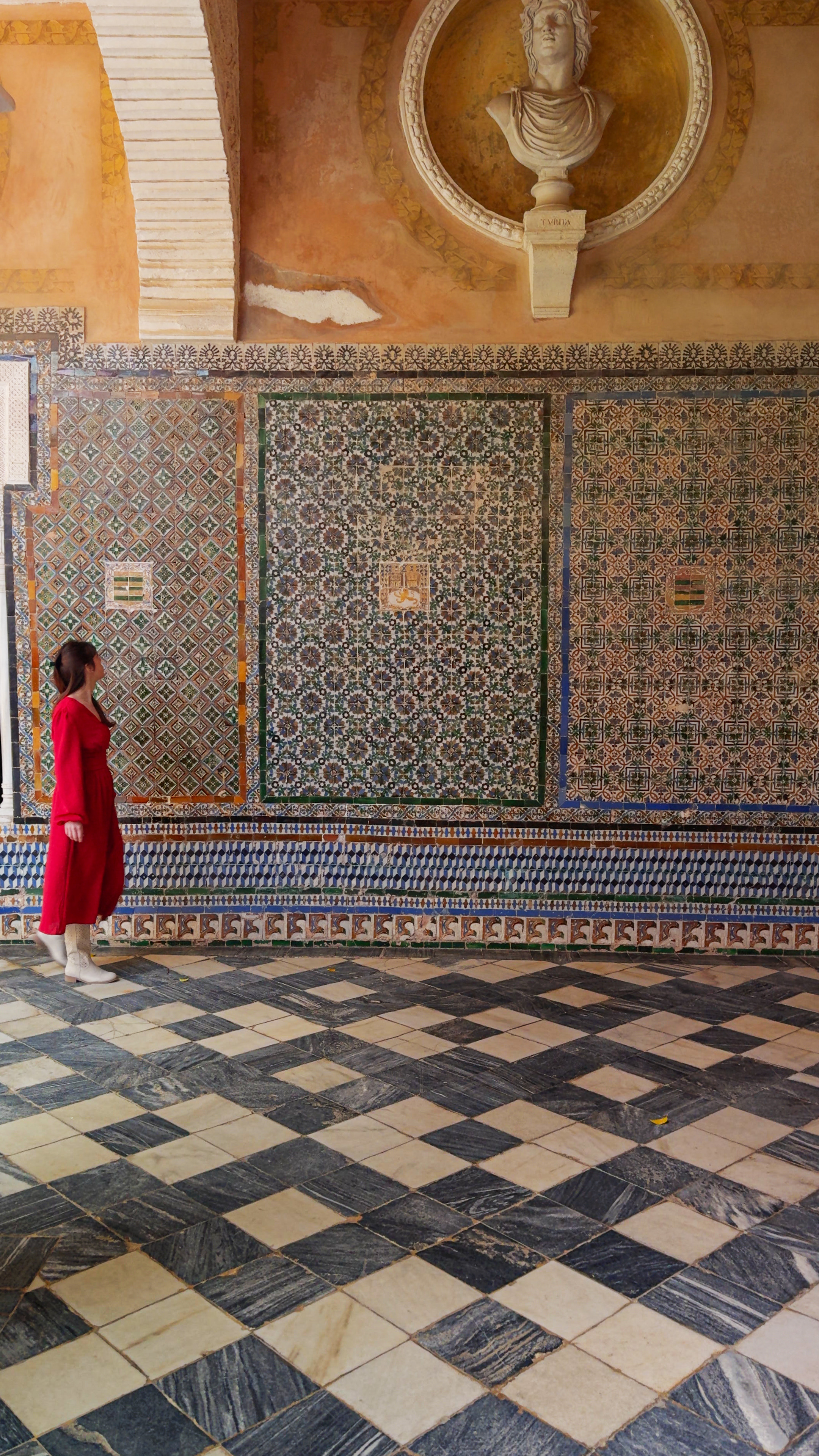 A small figure in a red dress in a tiled Moorish courtyard with a fountain