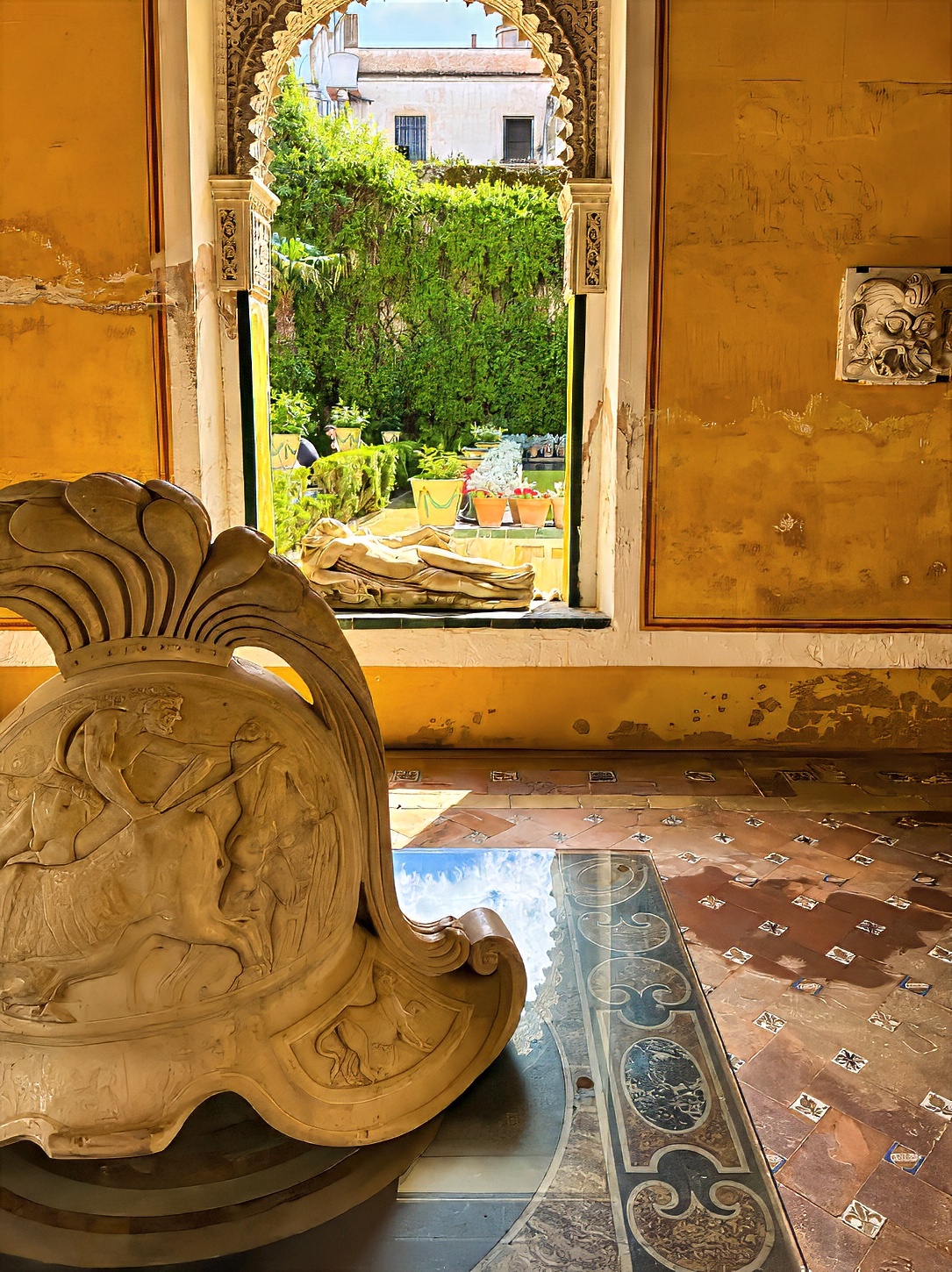 A carved stone fragment beside an open window onto a green garden