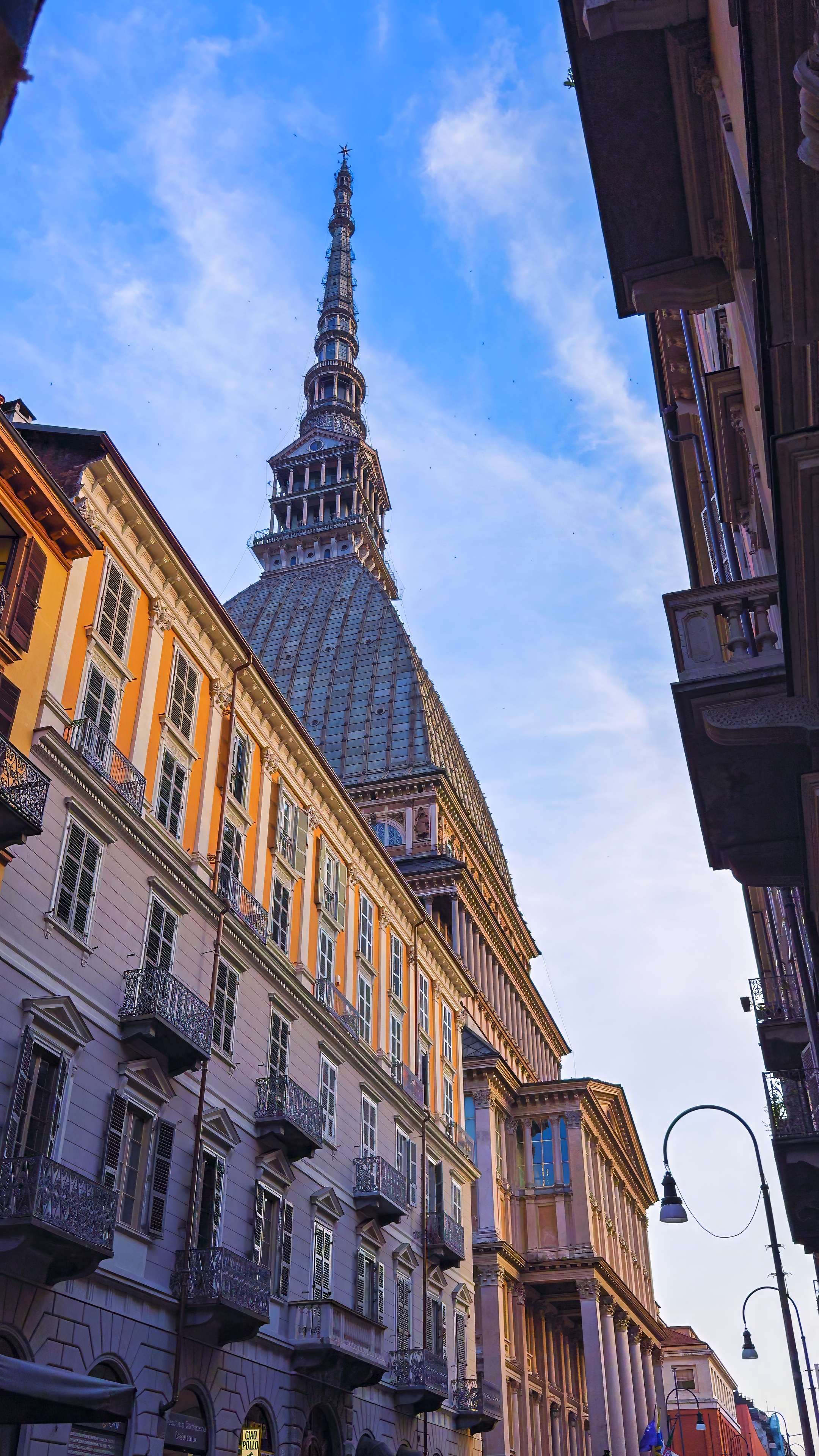The spire of the Mole Antonelliana rising above a street of yellow façades.