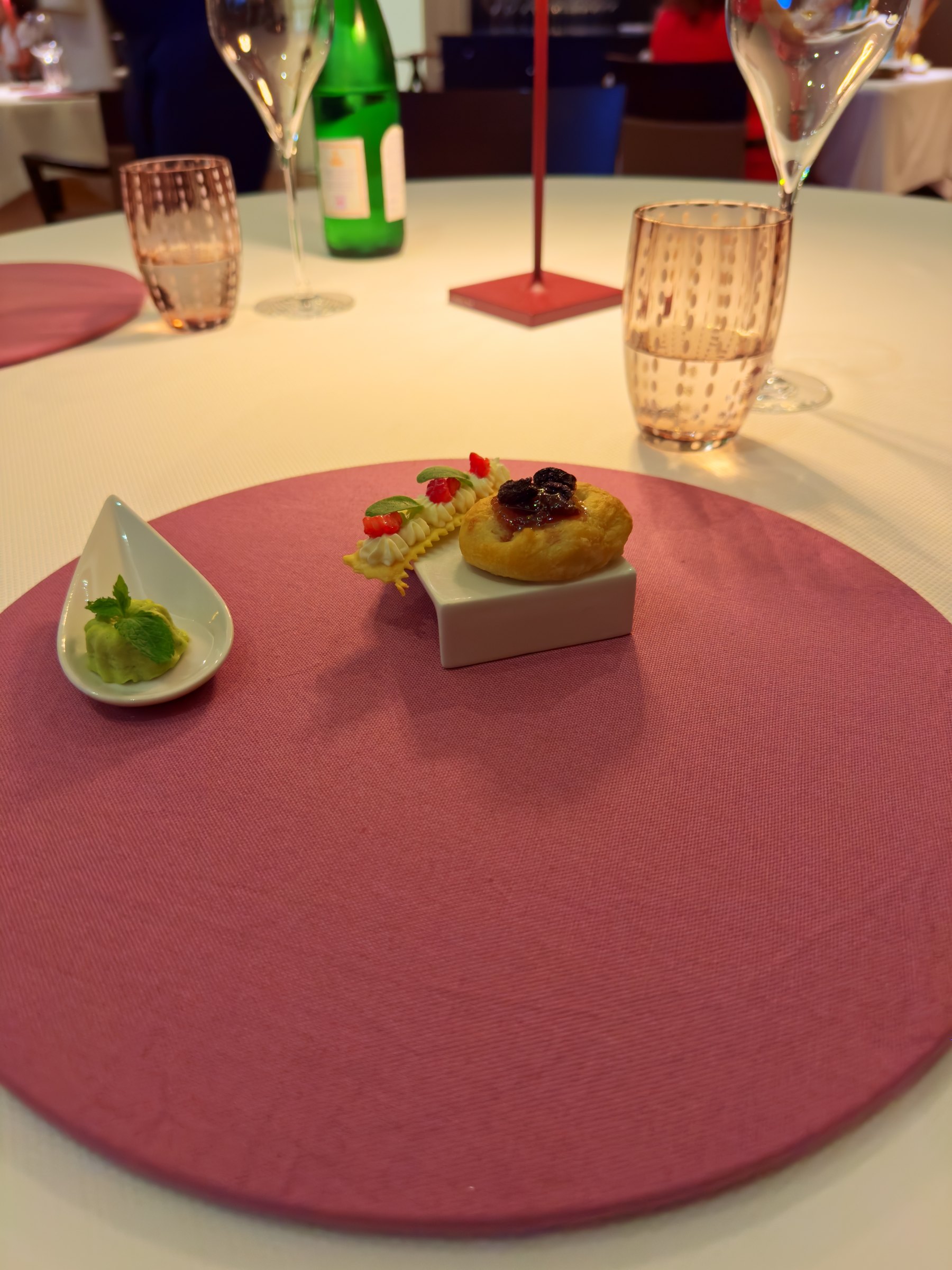 A composed plate on a raspberry-coloured charger, with a small white cup beside it
