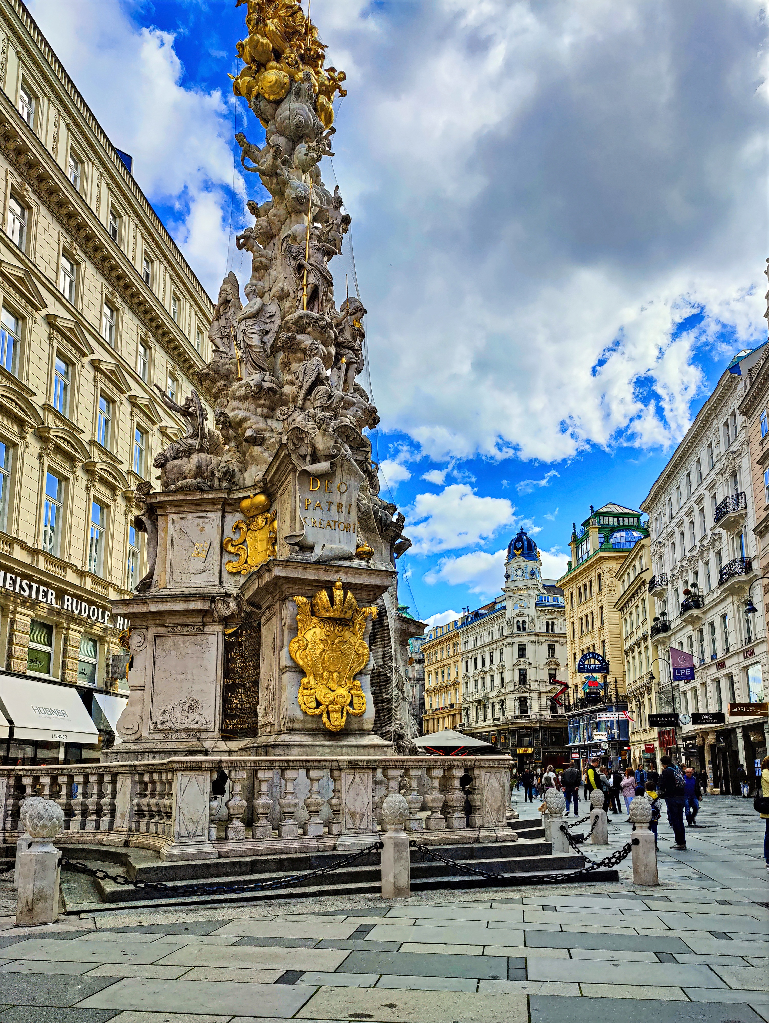 The baroque Plague Column on the Graben in Vienna, with gilded sculpture, stone balustrade and nineteenth-century facades on either side of the street.